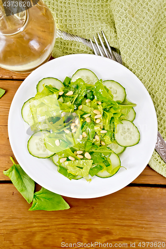 Image of Salad from spinach and cucumber with cedar nuts on board top