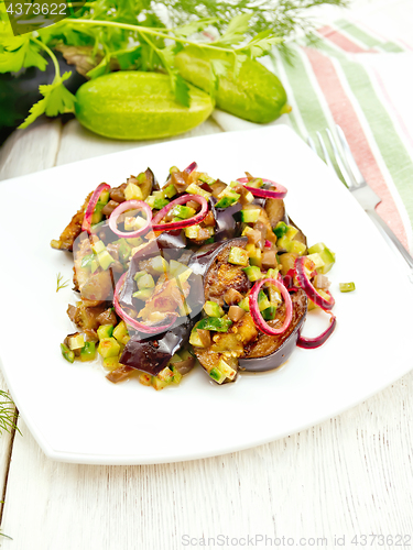 Image of Salad from eggplant and cucumber with onion in plate on light bo
