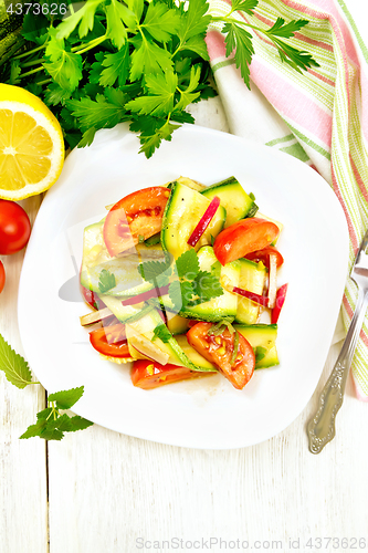Image of Salad with zucchini and tomato in plate on light board top