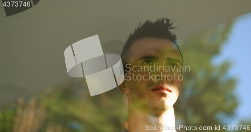 Image of reflection of sad man looking through window