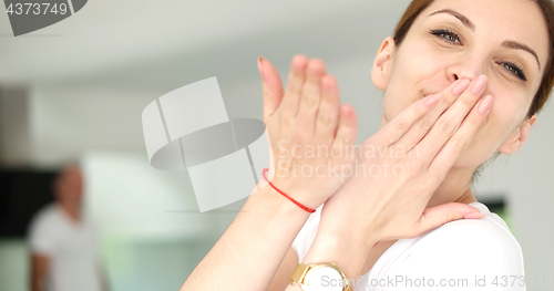 Image of woman sending kiss to camera in modern apartment