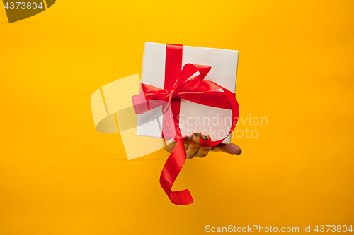 Image of close-up of female hand holding a present through a torn paper, isolated