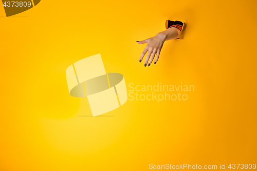 Image of Woman hand making sign through a hole in paper