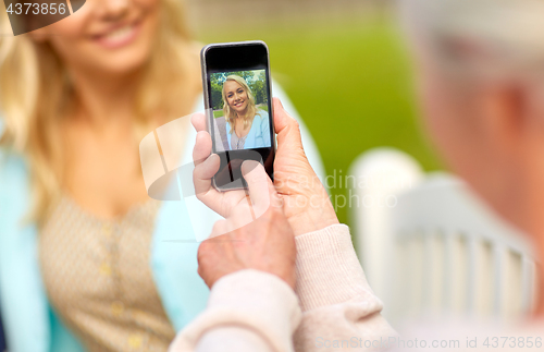 Image of senior mother photographing daughter by smartphone