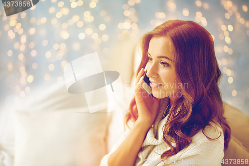 Image of happy young woman calling on smartphone at home