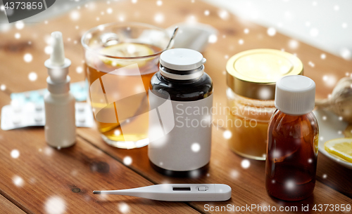 Image of drugs, thermometer, honey and cup of tea on wood