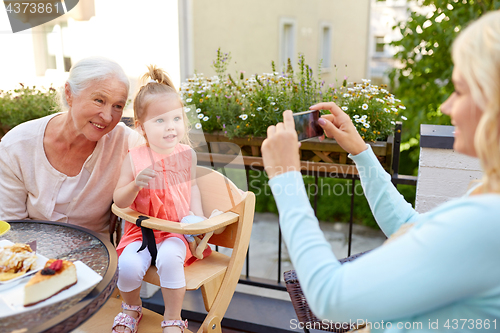 Image of woman photographing her family at cafe
