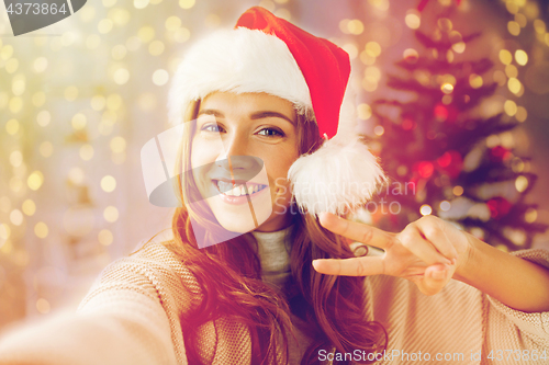 Image of happy woman taking selfie over christmas tree