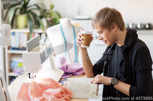 Image of fashion designer with coffee and book at studio