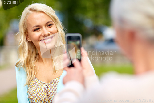 Image of senior mother photographing daughter by smartphone