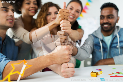 Image of team making thumbs up hand sign at office party