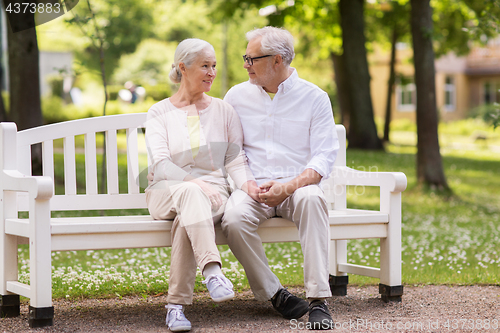 Image of happy senior couple sitting on bench at park