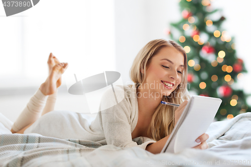 Image of happy woman with notebook in bed at christmas