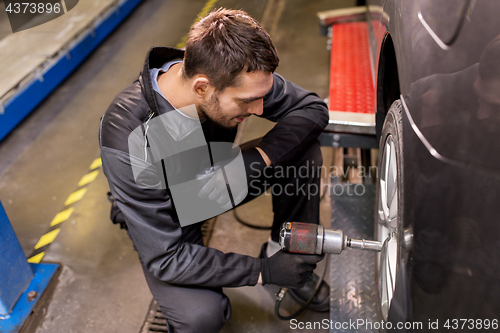 Image of auto mechanic with screwdriver changing car tire