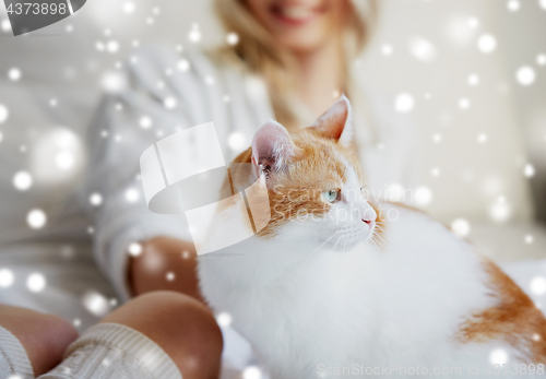 Image of happy young woman with cat in bed at home