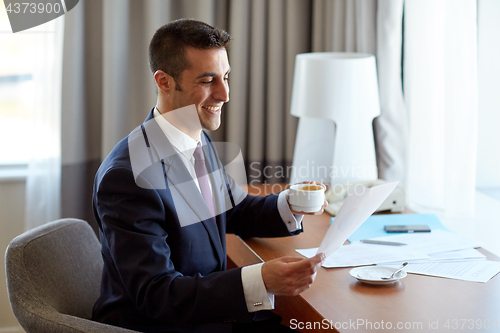 Image of businessman with papers drinking coffee at hotel