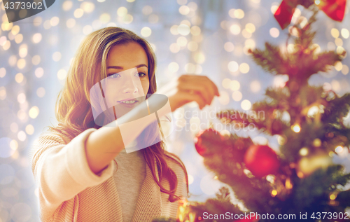 Image of happy young woman decorating christmas tree