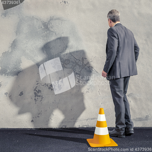 Image of a business man facing a dirty wall