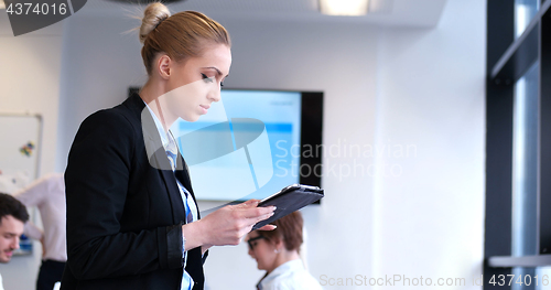 Image of Businesswoman using tablet with coworkers in backgorund having m