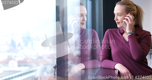 Image of Elegant Woman Using Mobile Phone by window in office building