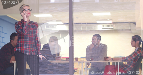 Image of Business Woman Looking Through A Window And using On A Cell Phon