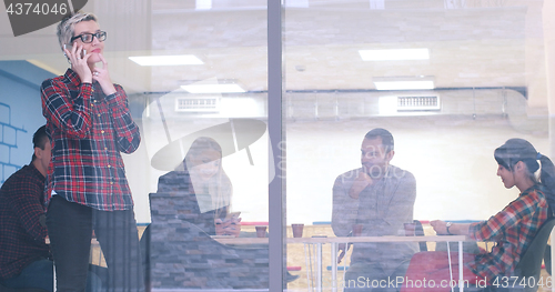 Image of Business Woman Looking Through A Window And using On A Cell Phon