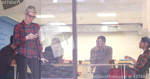 Image of Business Woman Looking Through A Window And using On A Cell Phon