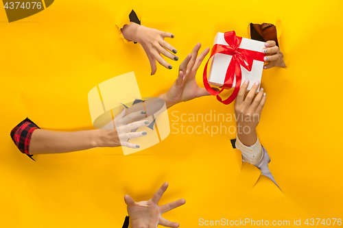 Image of close-up of female hand holding a present through a torn paper, isolated