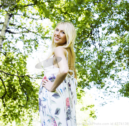 Image of happy blond young woman in park smiling