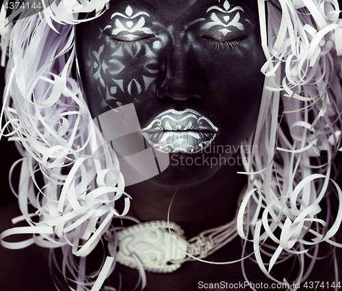 Image of creative makeup like Ethiopian mask, white pattern on black face close up, halloween celebration