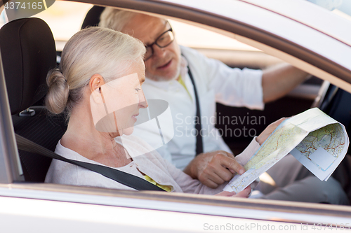 Image of happy senior couple with map driving in car