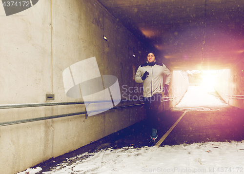 Image of happy man running along subway tunnel in winter