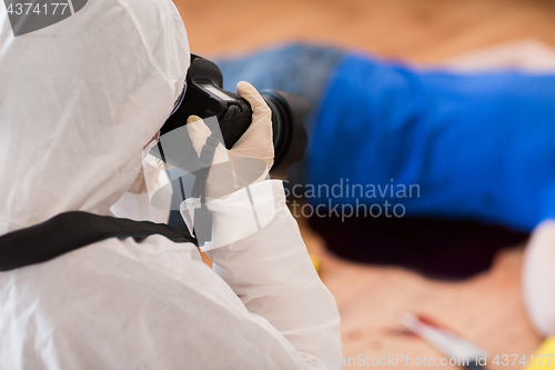 Image of criminalist photographing dead body at crime scene