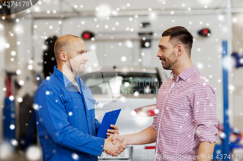 Image of auto mechanic and man shaking hands at car shop