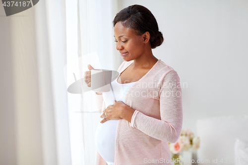 Image of happy pregnant woman with cup drinking tea at home