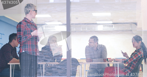 Image of Business Woman Looking Through A Window And using On A Cell Phon