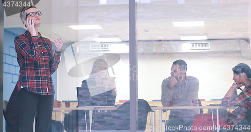 Image of Business Woman Looking Through A Window And using On A Cell Phon