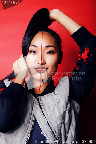 Image of young pretty asian girl posing cheerful on red background, fashion style makeup and hair, lifestyle modern orient people concept