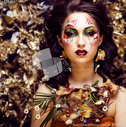 Image of beauty woman with face art and jewelry from flowers orchids clos