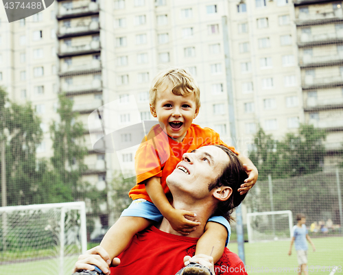 Image of outdoor lifestyle people concept, happy family: father and son playing football together