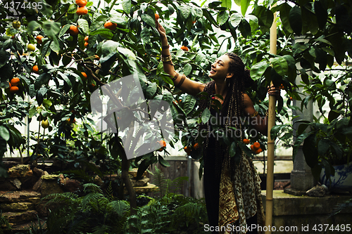 Image of Young cute smiling woman in park with oranges