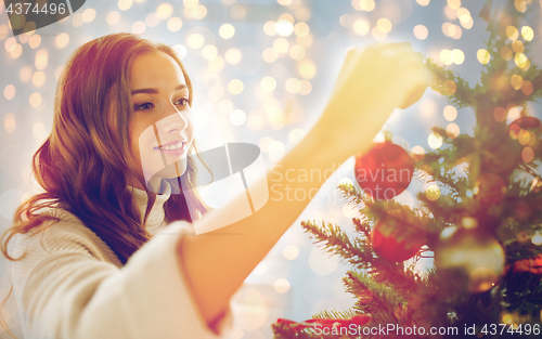 Image of happy young woman decorating christmas tree