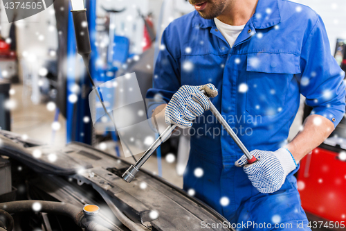 Image of mechanic man with wrench repairing car at workshop