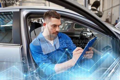 Image of auto mechanic man with clipboard at car workshop