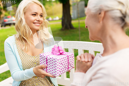 Image of daughter giving present to senior mother at park