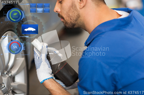 Image of mechanic with screwdriver changing car tire
