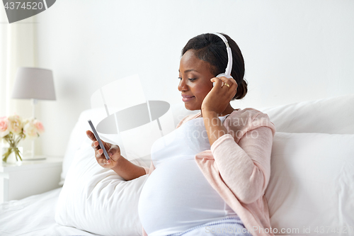 Image of pregnant woman in headphones with smartphone