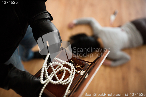 Image of criminal with knife and jewelry at crime scene