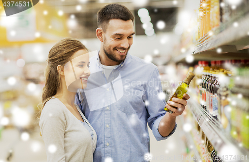 Image of happy couple buying olive oil at grocery store