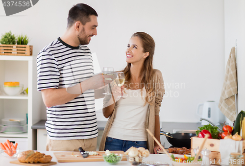 Image of couple cooking food and drinking wine at home